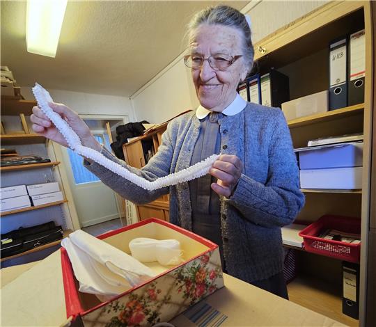 Schwester Lydia hält einen Teil einer früheren Diakonissen-Haube zwischen ihren Händen. Der filigran gefaltetete Stoffstreifen wird mit weiterem Hauben-Zubehör in einem Kästchen aufbewahrt. Fotos: Potthast