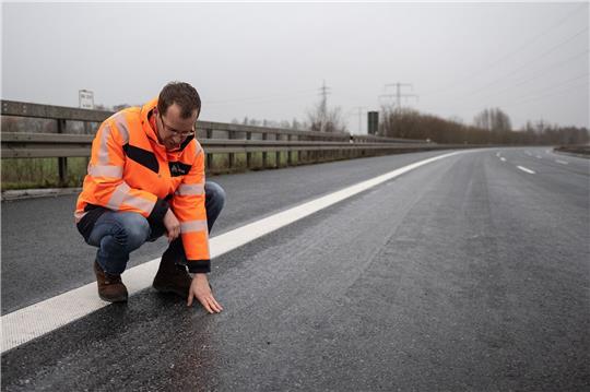 Sebastian Post, Leiter der Außenstelle der Autobahngesellschaft, hockt auf der gesperrten Fahrbahn der Autobahn 7.