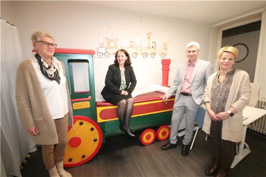 Seesens neue Kinderärztin Mihaela Kossmann sitzt auf der Behandlungsliege, die in eine Holzlok integriert ist. Daneben ihr Mann Manuel, zum Praxisteam gehören auch die medizinischen Fachangestellten Miriam Basile (li.) und Petra Orte.  Foto: Gereke