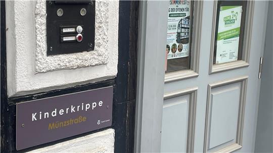 Tür mit grauem Rahmen und schwarzem Klingelschild mit der Aufschrift 'Kinderkrippe'