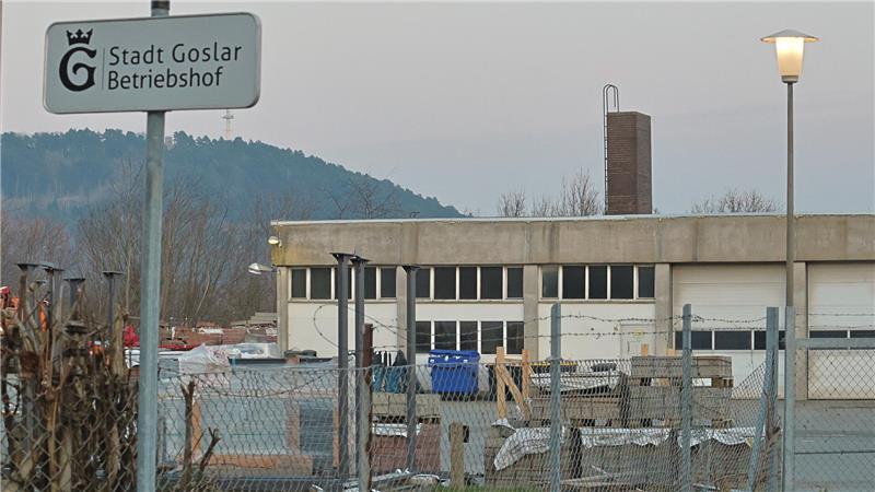 Außenbereich eines Betriebshofs mit einem Schild 'Stadt Goslar Betriebshof', mehreren Containern, Zäunen und einer Straßenlaterne vor einem Gebäude und bewaldetem Hügel im Hintergrund