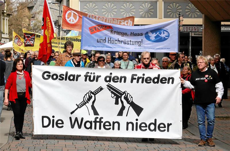 Goslarer Friedensbündnis wünscht deutliches Signal für anderen Kurs Demonstrierende Menschen auf einer Fußgängerzone halten ein Banner mit der Aufschrift 'Goslar für den Frieden Die Waffen nieder' und einer Grafik von zwei ineinandergreifenden Gewehren