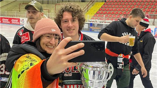 Selfie mit dem Kapitän: Nico Ehmann lächelt fürs Foto mit dem Pokal in der Hand. Im Hintergrund beobachtet Jung-Papa Andre Gerartz (mit Kappe) die Szenerie.