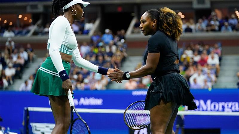 Serena Williams (r) und Venus Williams klatschen sich während des Spiels ab.