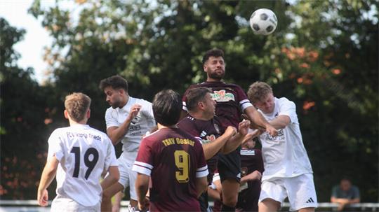 Mehrere Fußballspieler springen und kämpfen um einen Ball in der Luft während eines Spiels im Freien