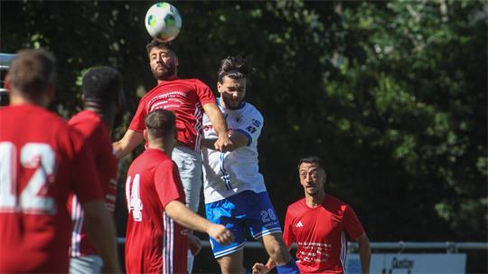Mehrere Fußballspieler in roten und weißen Trikots springen im Kampf um den Ball in der Luft