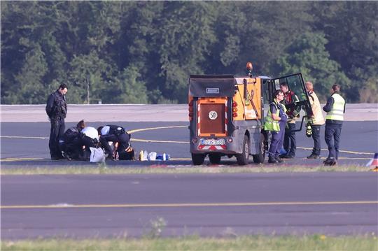 Sicherheitspersonal und Polizisten versuchen am Düsseldofer Flughafen, Aktivisten vom Asphalt auf dem Rollfeld zu lösen.