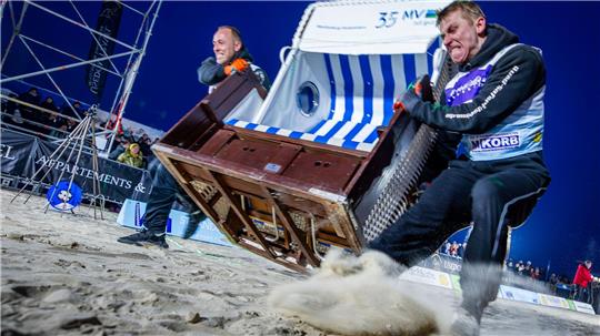 Sie geben alles: Das Team „Quad Safari Usedom“ mit Phillip Schmidt (l) und Finley Liemen (r) gewinnt den Finallauf bei der 18. Strandkorb Weltmeisterschaft auf der Insel Usedom mit einer neuen Weltrekordzeit von 4,56 Sekunden. Die Zweierteams müssen bei dem Wettkampf einen etwa 60 Kilogramm schweren Strandkorb über die 20 Meter lange Strecke über den Ostseestrand ins Ziel schleppen.