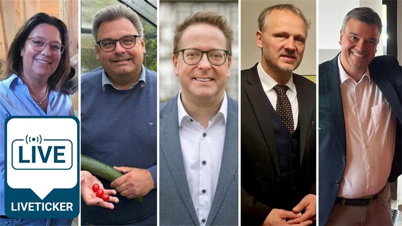 Mann in weißem Hemd und dunklem Sakko hebt lächelnd einen Blumenstrauß mit roter Folie hoch