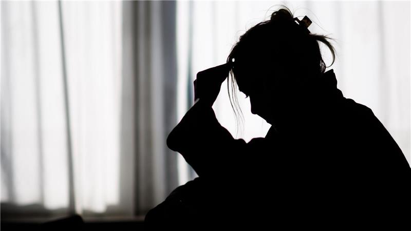 Silhouette einer Frau vor einer hellen Fensterfront