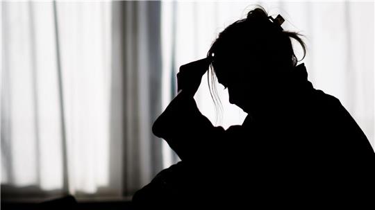 Silhouette einer Frau vor einer hellen Fensterfront