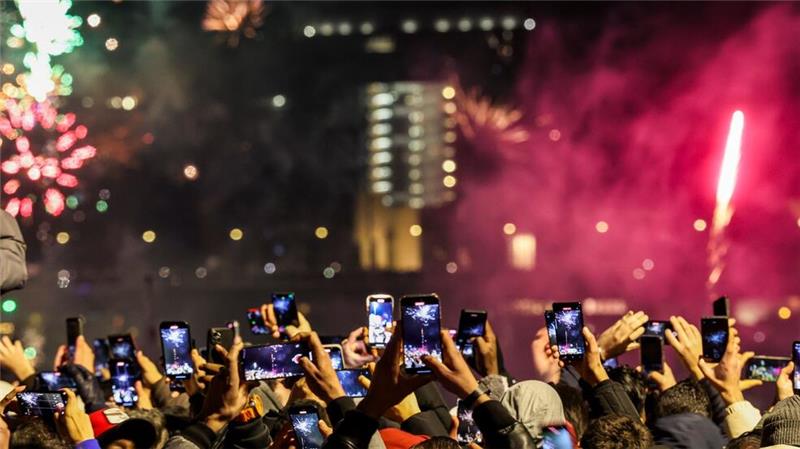 Silvester in Düsseldorf: Raketen zum neuen Jahr steigen in den Himmel, Tausende Menschen am Rheinufer feiern fröhlich.