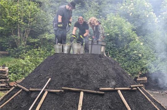 Simon Wiese und Christoph Michael zünden den Meiler an, mit Unterstützung eines Grundschülers.