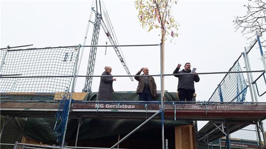 Simone Härtel (Leiterin vom Kindergarten St. Josef), Bernhard Düsing (Stellvertr. Kirchenvorstand) und Marvin Bremer (Holzbau Meinholz) sind bei dem Richtfest aufs Gerüst gestiegen.