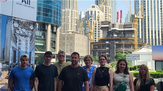 Mehrere Menschen stehen nebeneinander, im Hintergrund Hochhäuser.