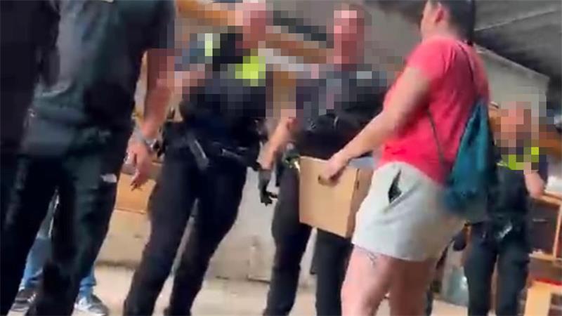 Polizeibeamte begleiten eine Aktenübergabe: Ein Mann hält eine Kiste mit Papieren in den Armen, drumherum stehen Polizeibeamte.