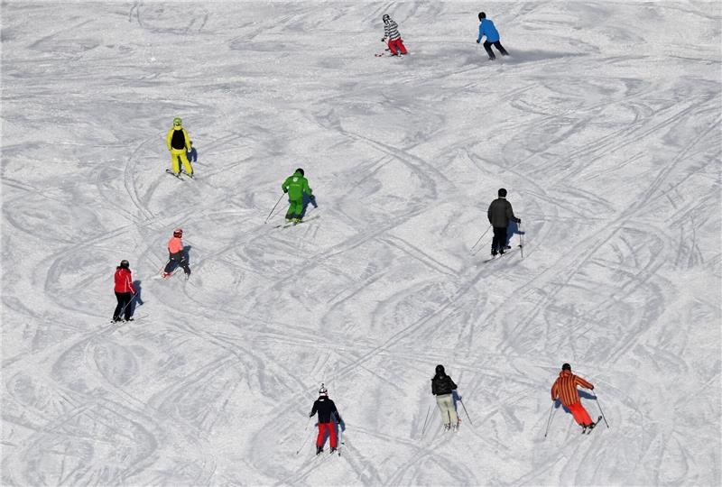 Skifahrer fahren bei Sonnenschein auf einer Skipiste.