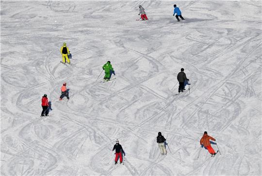 Skifahrer fahren bei Sonnenschein auf einer Skipiste.