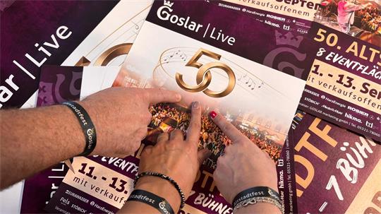 Handgelenke mit drei Armbändern, darunter ein schwarzes Stoffarmband mit weißer Aufschrift 'Altstadtfest'.