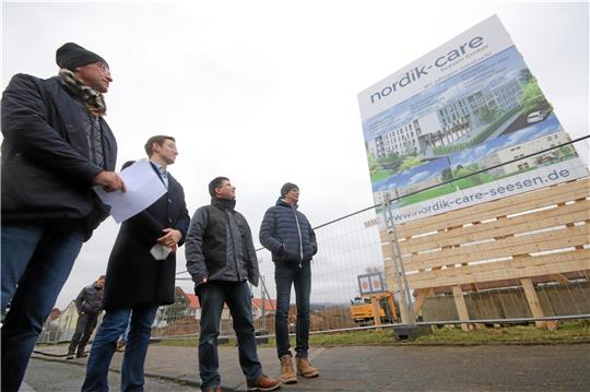 So soll es einmal aussehen (v.li.): Kenneth Woods, Dave Woods, Planer Holger Neubert und Bauleiter Rüdiger Otto blicken am Rande des Baugrunds auf das Schild, das darüber Auskunft gibt, was dort entsteht.  Fotos: Gereke