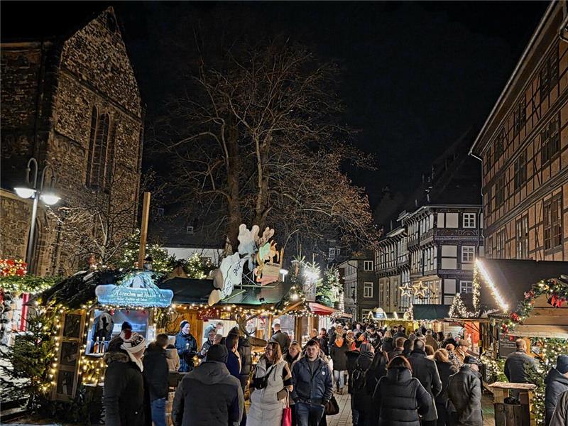 Zwischen den beleuchteten Weihnachtsmarkt-Buden laufen Menschen.