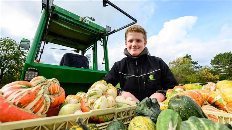 Sören Schulz, 15 Jahre alter Gemüsebauer, sitzt neben seinem Traktor und selbst angebauten Kürbissen. 