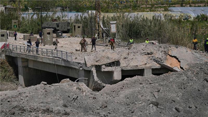 Soldaten und Zivilisten überqueren eine zerstörte Brücke, die bei einem israelischen Luftangriff nahe der Küstenstadt Tyrus im Libanon getroffen wurde.