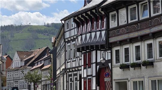 Fachwerkhäuser an einer Straße mit bewaldeten Hügeln im Hintergrund