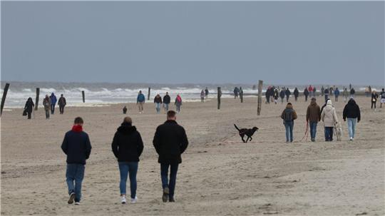 Spaziergänger am Strand der ostfriesischen Insel Norderney. 