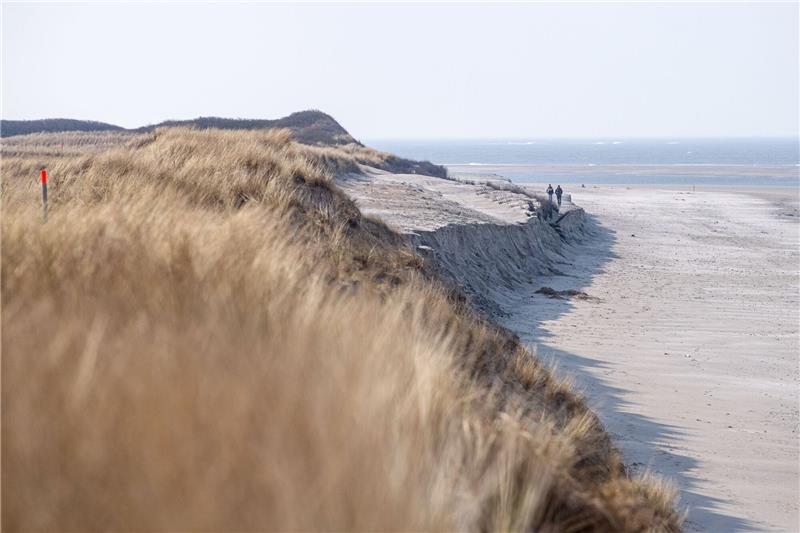 Küstenschutz bereitet Strandaufspülung auf Langeoog vor Spaziergänger laufen an der Abbruchkannte am Strand entlang.