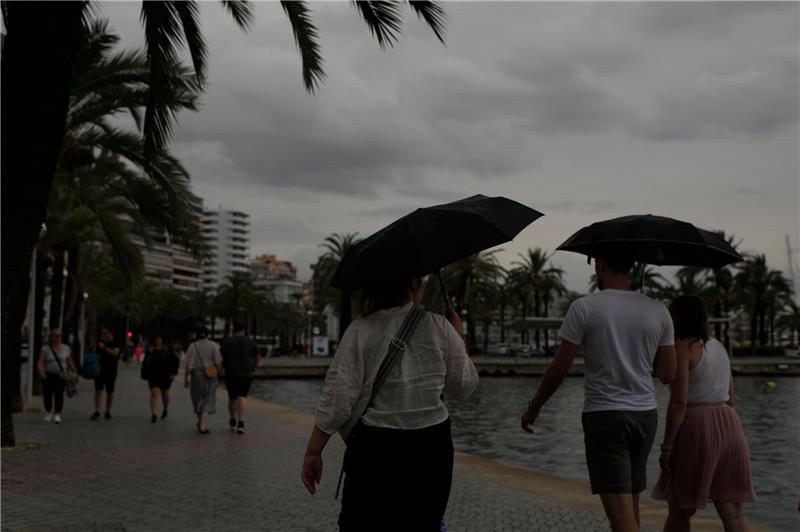 Rekord-Niederschläge: Starke Überschwemmungen auf Mallorca Spaziergänger mit Regenschirmen sind an der Strandpromenade von Palma unterwegs.