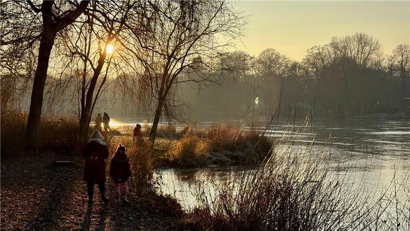 Spaziergänger sind am zugefrorenen Schloßteich in Chemnitz unterwegs.
