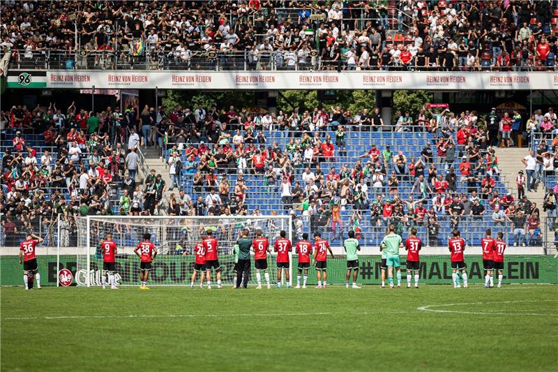 Spieler von Hannover 96 stehen nach Spielende vor der Tribüne mit Fans von Hannover.