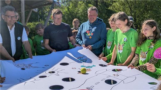 Spielerisch zeigen die Junior-Ranger gemeinsam mit Nationalparkleiter Roland Pietsch (3.v.l.), wie schwer es für Tiere ist, sich umgeben von Straßen zurechtzufinden. Mit dabei ist neben Bundesumweltminister Carsten Schneider (2.v.l.) und Niedersachsens Umweltminister Christian Meyer (nicht im Bild) auch Bürgermeister Wolfgang Langer (l.)