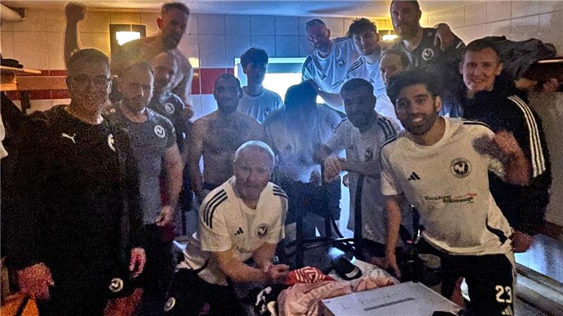 Gruppe von Fußballspielern in Umkleidekabine mit Trikots und Sporttaschen auf Bank