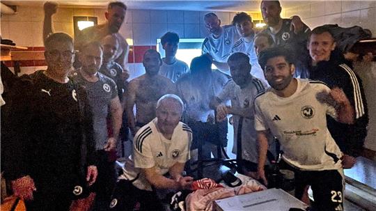 Gruppe von Fußballspielern in Umkleidekabine mit Trikots und Sporttaschen auf Bank