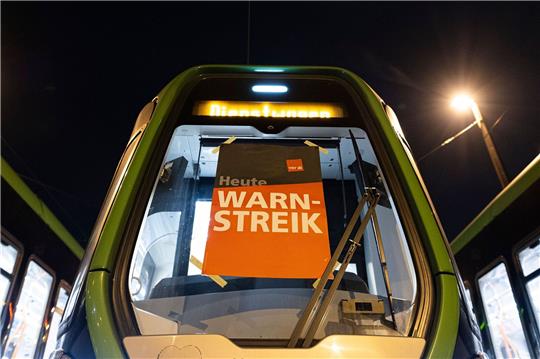 Stadtbahnen der hannoverschen Verkehrsbetriebe Üstra stehen auf dem Betriebshof Glocksee - auf einem Schild ist der Schriftzug «Heute Warnstreik» zu lesen.
