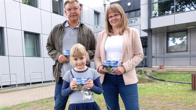 Ferienpass lockt mit 154 Angeboten Stadtjugendpfleger Jens Fiebig und Ferienpass-Koordinatorin Anja Magerl von der Stadtjugendpflege präsentieren mit der sechsjährigen Pia Fehse das druckfrische Produkt.