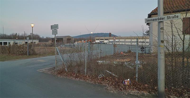 Straßenschild mit der Aufschrift 'Immenröder Straße' an einer Kreuzung in einem ländlichen Gebiet mit kahlen Büschen und einem Zaun