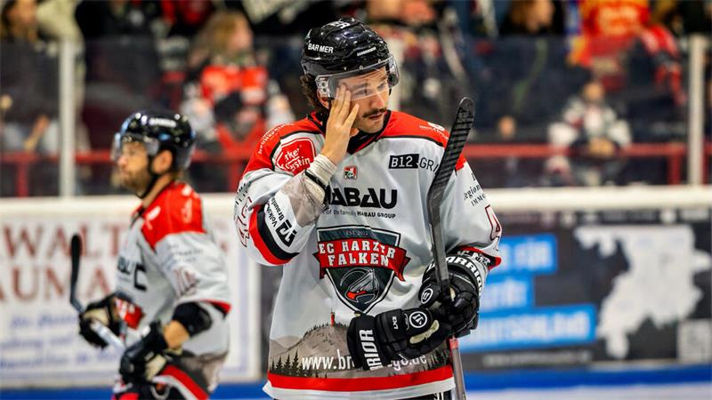 Ein Eishockeyspieler im weißen Trikot fasst sich ins Gesicht.