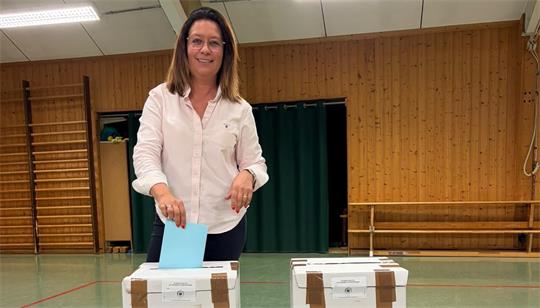 Eine Frau wirft einen Wahlzettel in eine Wahlurne. 