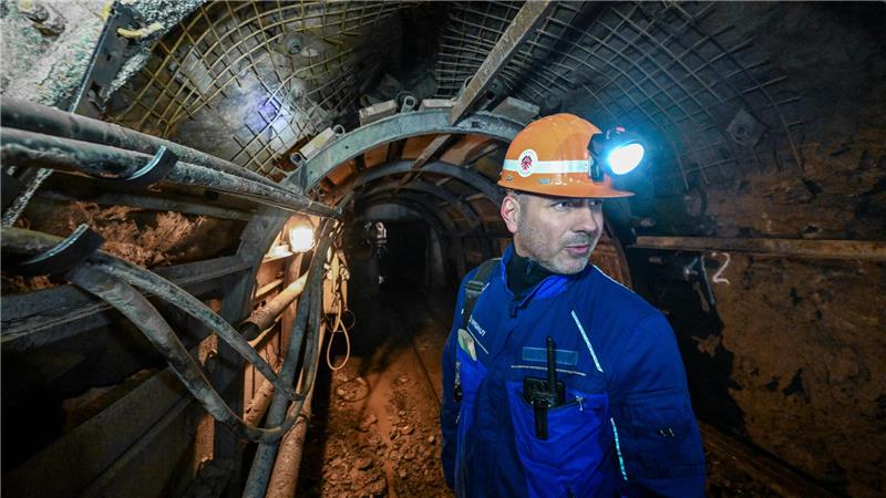 Ein Bergmann mit Kopflampe steht in einem Stollen.