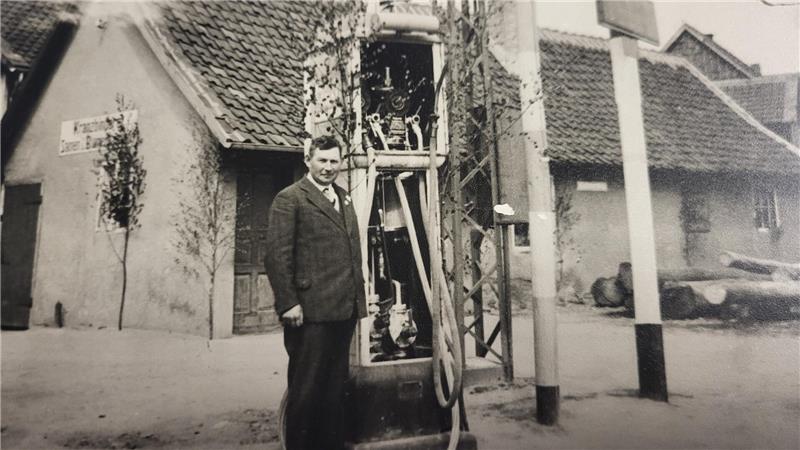 Nach 98 Jahren: Vienenburger Tankstelle Schnevoigt in neuen Händen Mann in Anzug steht neben einer alten Zapfsäule vor einem Gebäude mit Ziegeldach und Fenstern.