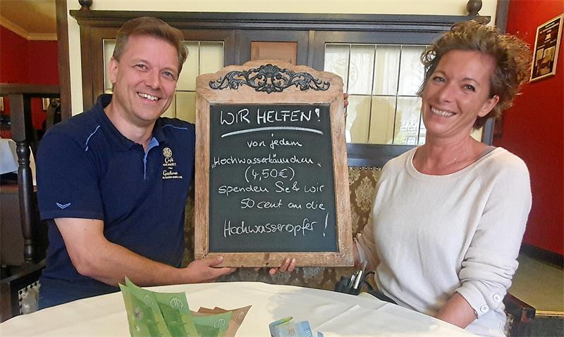 Mann und Frau halten ein Schild in die Kamera. 