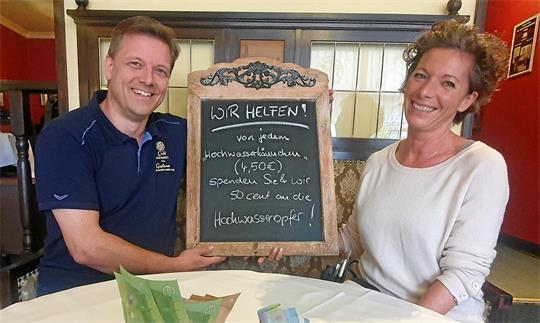 Mann und Frau halten ein Schild in die Kamera. 