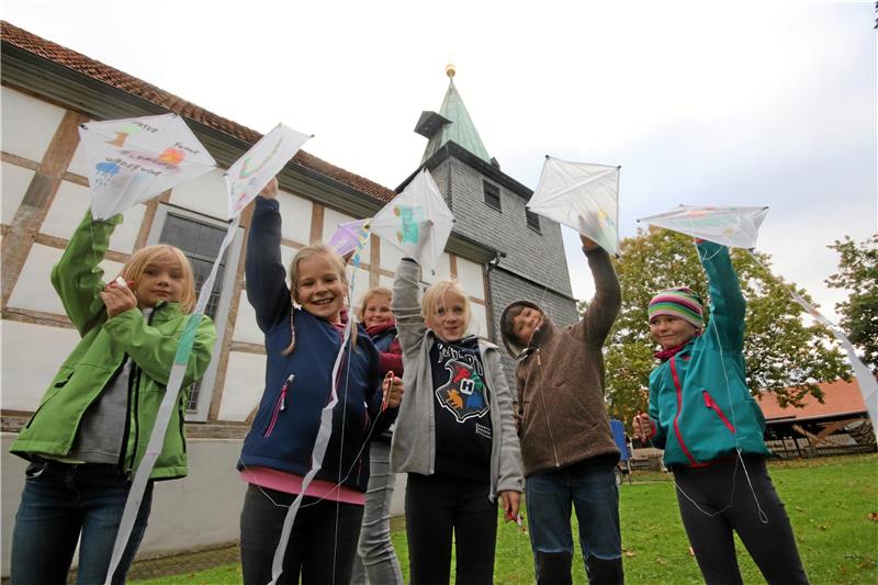 25. Schladener Kinderbibelwoche mit Rekordteilnahmerzahl Stolz präsentieren die Kinder ihre selbst gebauten Drachen – sie lassen sie gleich im Schatten von Schladens evangelischer Kirche steigen. Foto: Gereke