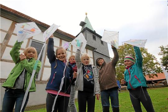 Stolz präsentieren die Kinder ihre selbst gebauten Drachen – sie lassen sie gleich im Schatten von Schladens evangelischer Kirche steigen. Foto: Gereke