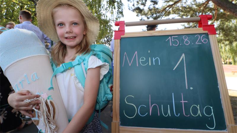 Ein Kind mit einer Schultüte an einer Kreidetafel mit der Aufschrift "Mein erster Schultag".