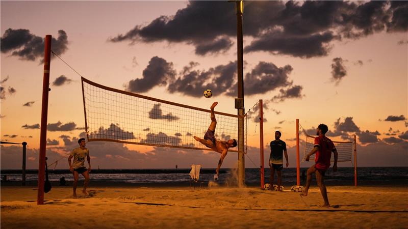 Strandbesucher spielen Fußball und Volleyball am Mittelmeer in Tel Aviv.