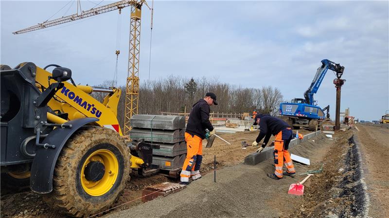 Straßenbauer bereiten derzeit alles dafür vor, dass die neue Fahrbahn gegossen werden kann. Parallel dazu wird bereits aufgeräumt, wie etwa durch das Herausziehen der Spundbohlen (Hintergrund).
